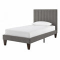Cama individual tapizada en poliéster gris con cabecero y patas de madera